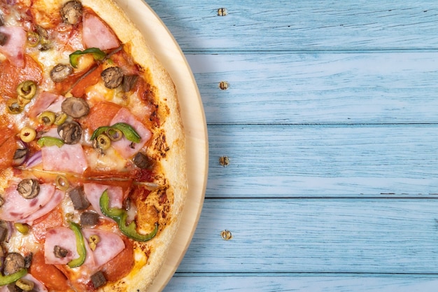 Heerlijke grote pizza met kalfsvlees en champignons op een blauwe houten ondergrond