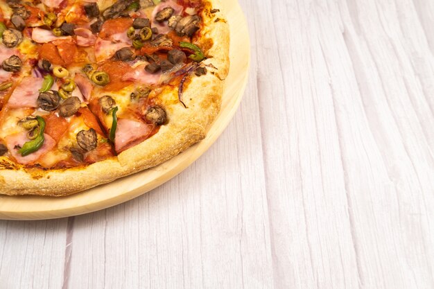 Heerlijke grote pizza met kalfsvlees en champignons op een lichte houten ondergrond