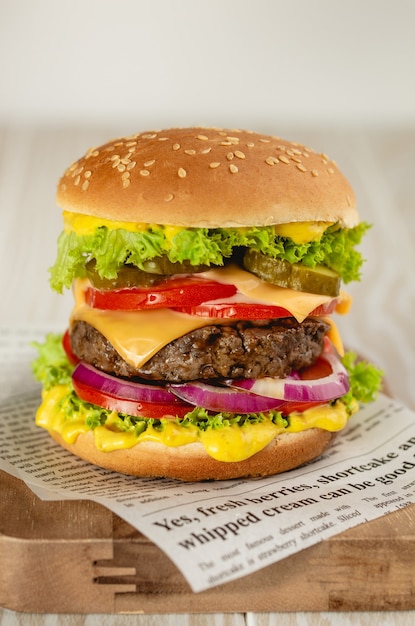 Heerlijke hamburger met vlees, gesmolten kaas, druipende saus en groenten op witte rustieke achtergrond. Vers gemaakte smakelijke hamburger, close-up
