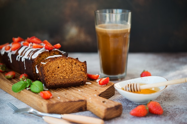 Heerlijke honingcake voor thee gedecoreerd met suiker Fudge en verse rode aardbeien. Horizontale oriëntatie.