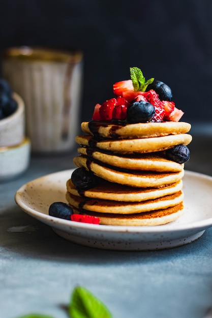 Heerlijke huisgemaakte vegetarische haver pannenkoeken met bosbessen, aardbeien, munt en chocoladesaus