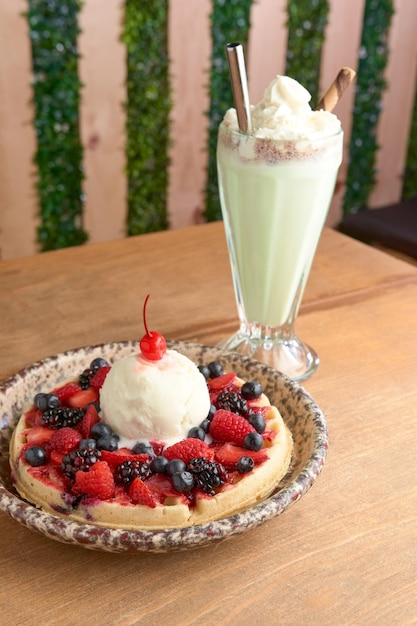 Heerlijke ijswafel met rode fruitscherry en shake op houten tafel