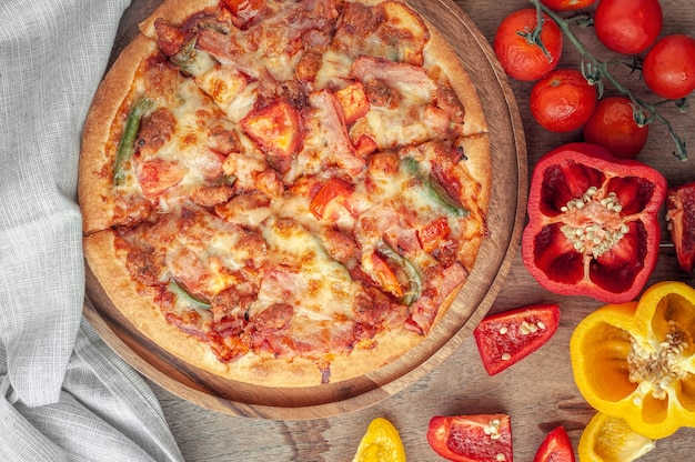 Heerlijke Italiaanse pizza gesneden met spek, kaas, tomaat, paprika op houten plaat