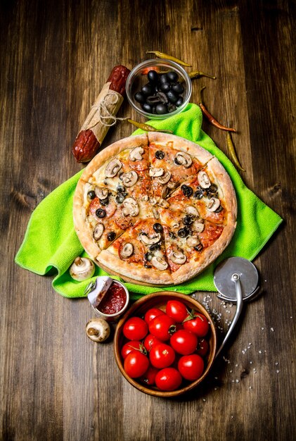 Heerlijke Italiaanse pizza op de stof. Op een houten tafel. Bovenaanzicht