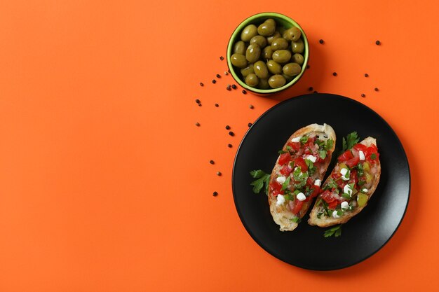 Heerlijke Italiaanse snacksbruschetta en ingrediënten op oranje achtergrond