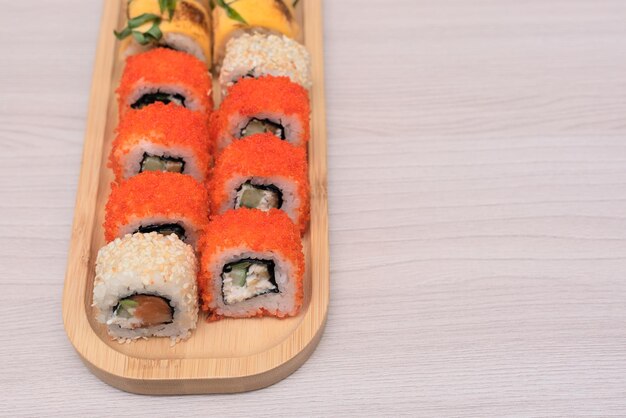 Heerlijke Japanse broodjes met zalm, avocado, komkommerkaas op houten plaat met selectieve focus Aziatisch voedselconcept Gezond eten