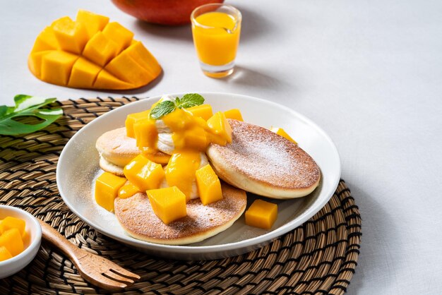 Heerlijke Japanse souffle pannenkoek met dobbelstenen mango en jam op witte tafel achtergrond