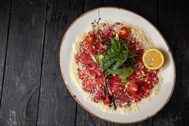 Heerlijke kalfscarpaccio op een bord op een donkere houten tafel