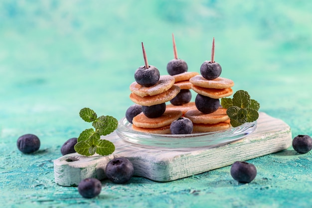 Heerlijke kleine pannenkoekjes en verse bosbessen aan spiesjes. Nieuw foodtrendconcept.