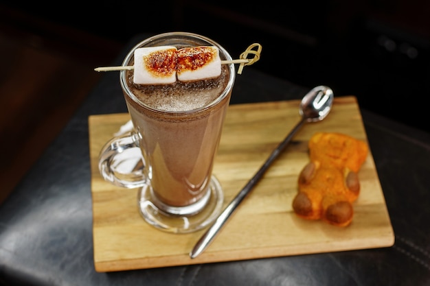 Heerlijke koffiecocktail met marshmallows met teddybeerkoekjes op een houten bord