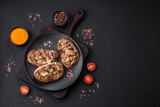 Heerlijke krokante toast of bruschetta met gebakken ui champignon champignons en kaas met specerijen en kruiden op een donkere betonnen achtergrond