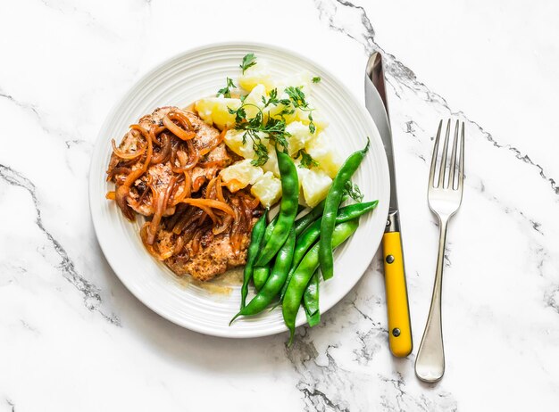 Heerlijke lunch pork chop romige aardappelen en sperziebonen op een licht marmeren bovenaanzicht als achtergrond