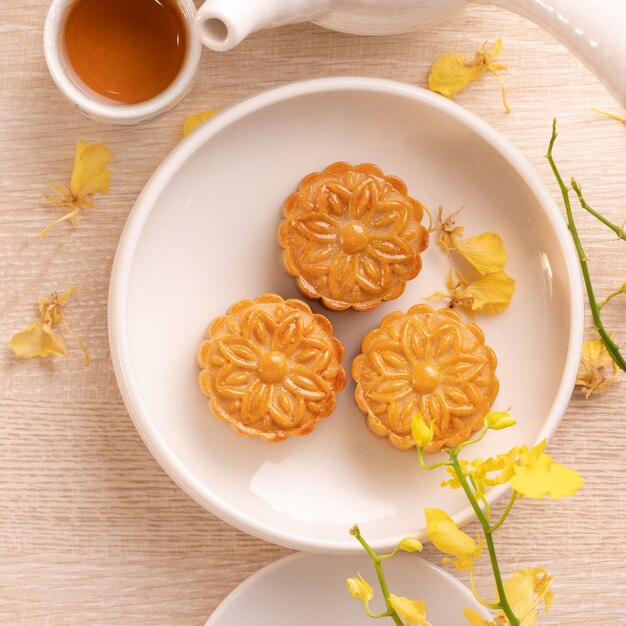 Heerlijke maancake voor Mid-Autumn festival met prachtig patroon, versierd met gele bloemen en thee