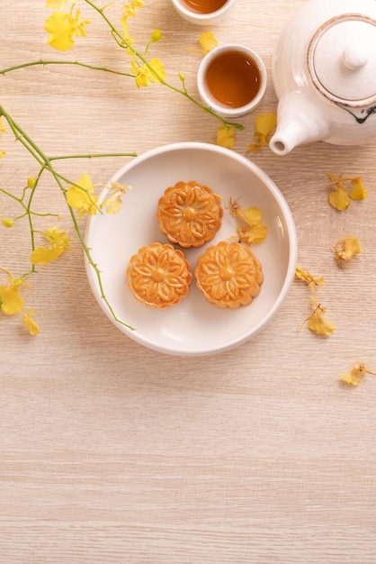 Heerlijke maancake voor MidAutumn-festival met prachtig patroon versierd met gele bloemen en thee Concept van feestelijk middaggebakontwerp