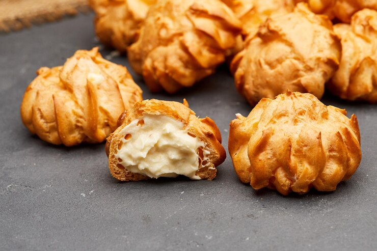 Heerlijke met room gevulde profiteroles op een donker leisteenoppervlak, perfect voor dessertliefhebbers