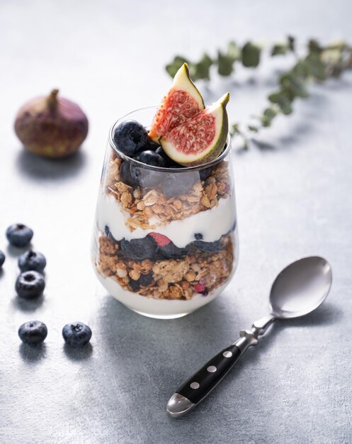 Heerlijke natuurlijke yoghurt met muesli en bessen in een glas op een blauwe achtergrond