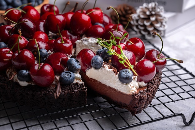 Foto heerlijke nutella pure chocoladetaart met kersen en bosbessen op het zwarte rek. detailopname.