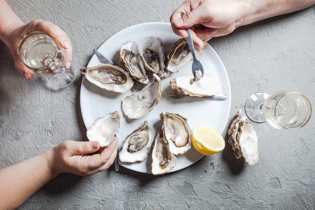 Heerlijke oesters met schijfje citroen en glazen witte wijn, bovenaanzicht