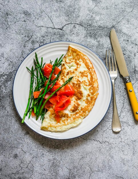 Heerlijke ontbijtbrunchomelet met asperges en gerookte zalm op een grijze bovenaanzicht als achtergrond