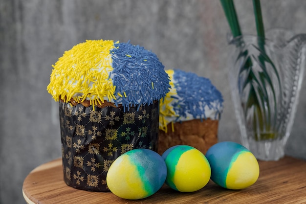 Heerlijke paascakes in de kleuren van de vlag van Oekraïne geelblauw gekleurde paaseieren op een houten tafel met bloemen op de achtergrond plaats voor tekst selectieve focus