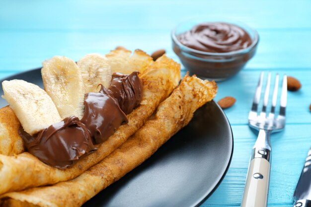 Heerlijke pannenkoeken met chocolade en banaan op blauwe houten tafel