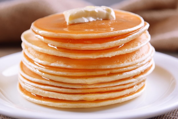 Heerlijke pannenkoeken met honing op plaat op tafel close-up