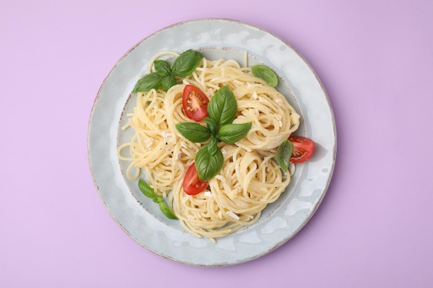 Heerlijke pasta met brie kaastomaten en basilicumblaadjes op violette achtergrond bovenaanzicht