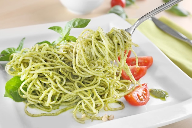 Heerlijke pasta op vork met pesto saus over bord close-up