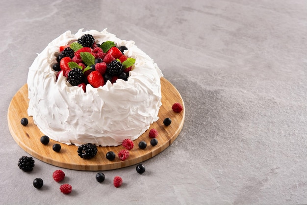 Heerlijke Pavlova cake met meringue gegarneerd en verse bessen op grijze steen