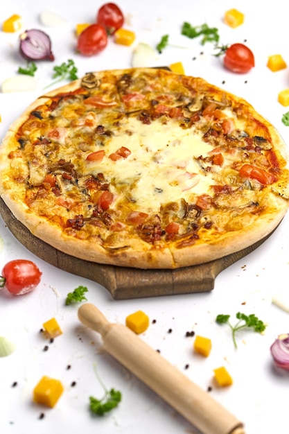 Heerlijke pizza met tomaat, champignons, smeltkaas en spek op houten plaat. Witte achtergrond, smakelijke samenstelling.