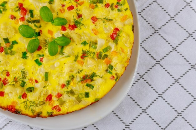 Heerlijke plantaardige omelet geserveerd in witte plaat.