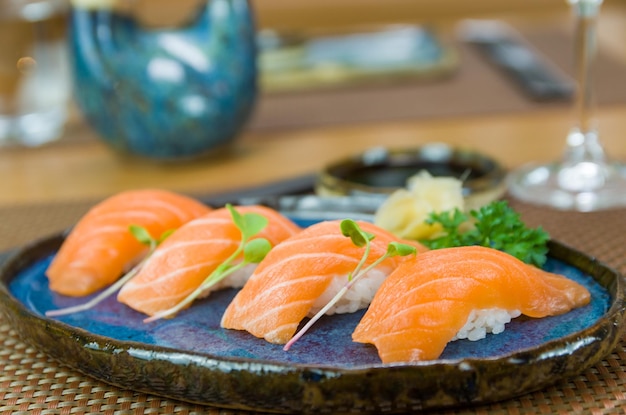 Heerlijke premium zalm nigiri op blauw handgemaakt bord versierd