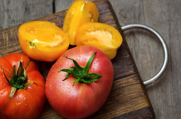 Heerlijke rode en gele tomaten op houten snijplank.