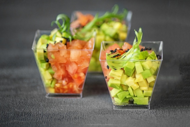 Heerlijke salade met avocado en tomaten op een grijze achtergrond Close-up Concept voor voedsel dieet en gezonde voeding restaurant en catering