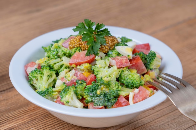 Heerlijke salade met broccoli-tomatenui en gekookt ei met roomsaus in plaat op houten achtergrond Gezonde voeding