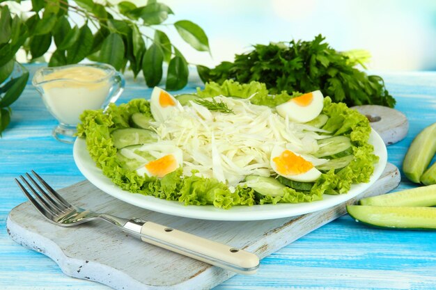 Heerlijke salade met eieren, kool en komkommers op blauwe houten tafel