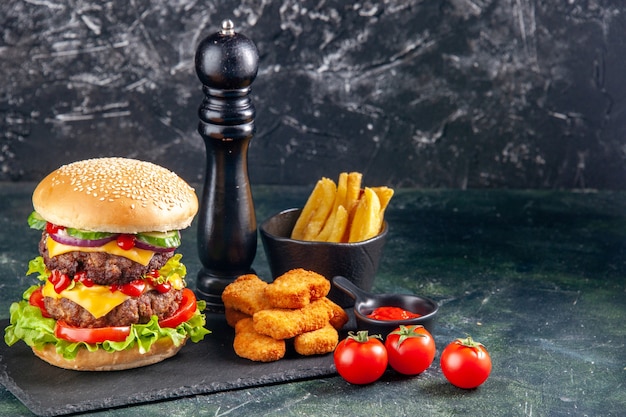 Heerlijke sandwich en kipnuggets frietjes op donkere kleur dienblad tomaten op zwarte ondergrond