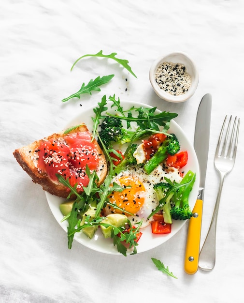 Heerlijke sandwich volkoren toast met gepocheerd ei cherrytomaatjes avocado en rucola op een lichte achtergrond bovenaanzicht