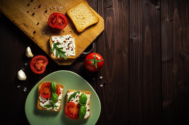 Heerlijke sandwiches roomkaas met tomaten op een donkere houten achtergrond