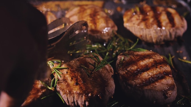 Heerlijke sappige vleesbiefstuk koken op de grill Oud prime zeldzaam gebraden grillen marmer rundvlees Elektrische koffiebrander rozemarijn zwarte peper zout Keukentang