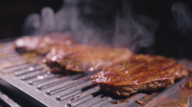 Heerlijke sappige vleesbiefstuk koken op grill Prime beef fry op elektrische braadpan rozemarijn zwarte peper zout Slow motion