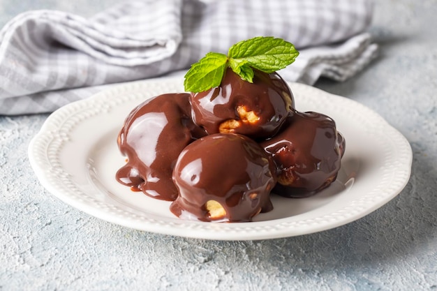 Heerlijke soesjes met chocolade en wit bord. Selectief focusbeeld op lichte achtergrond.