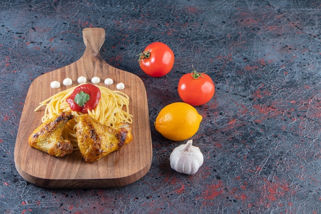 Heerlijke spaghetti en kippenvleugels op een houten bord met groenten.