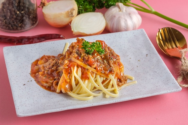 Heerlijke spaghetti met bolognesesaus die op een witte vierkante plaat wordt gediend
