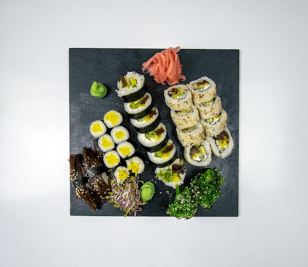 Heerlijke sushi set met sojasaus en eetstokjes op zwarte stenen plaat