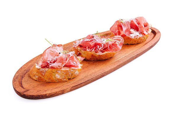 Heerlijke tapas met gekookte ham op knapperig brood geserveerd op een houten schotel
