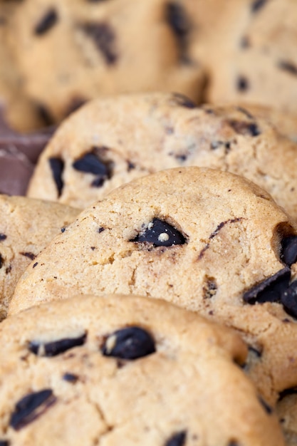 Heerlijke tarwemeelkoekjes en chocoladedruppels in het voorbereide zandkoekdeeg, zelfgemaakte koekjes van onregelmatige ronde of ovale vorm samengevouwen, close-up