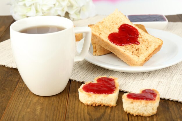 Heerlijke toast met jam en kopje thee op tafel close-up