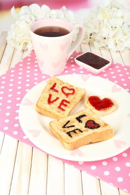 Heerlijke toast met jam en kopje thee op tafel close-up