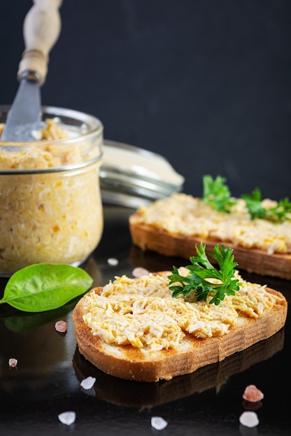 Heerlijke toastjes met huisgemaakte kiprillettes. Sandwichsnack met kippenpastei op donkere achtergrond